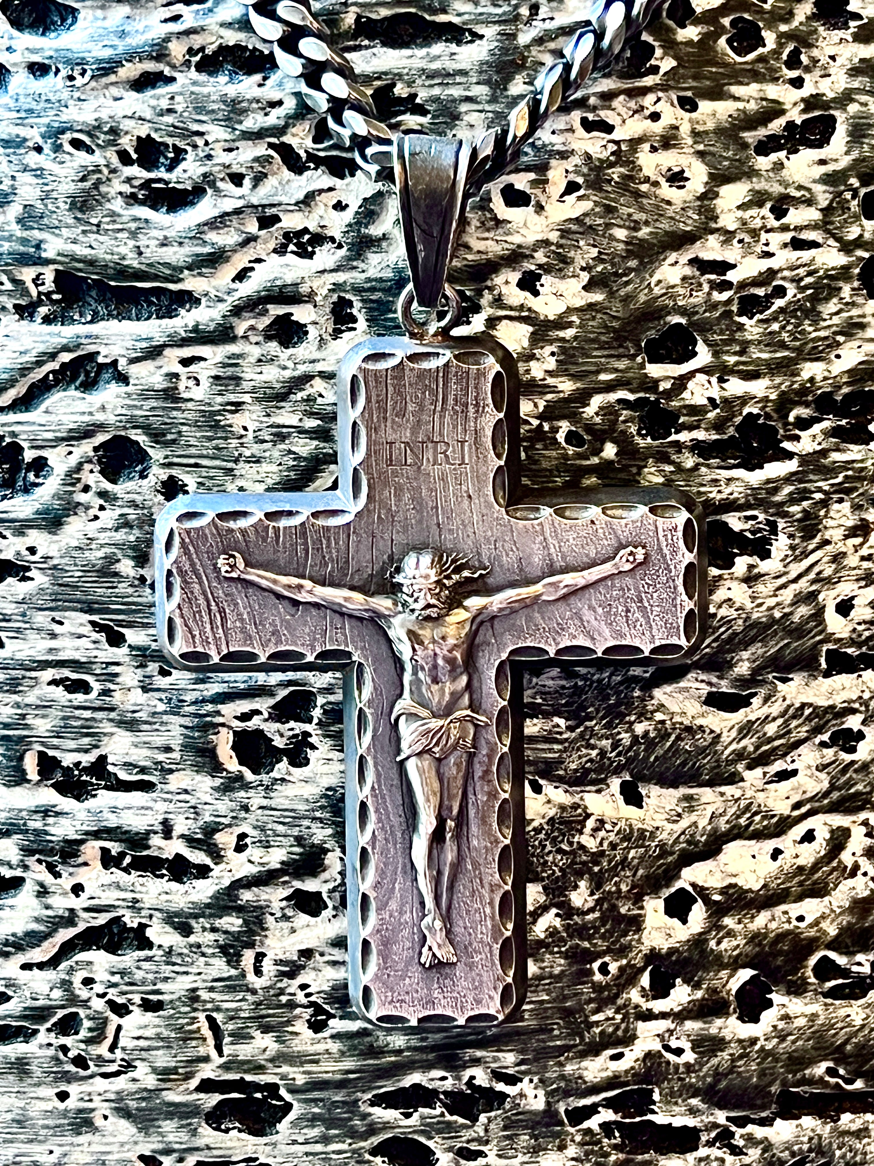 Cross pendant with Jesus Christ figure on a textured metal surface