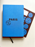 Blue notebook with 'PARIS' and Louis Vuitton logo on a white background