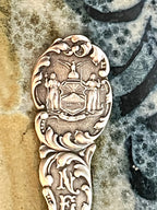 Decorative silver spoon with intricate designs on a stone surface