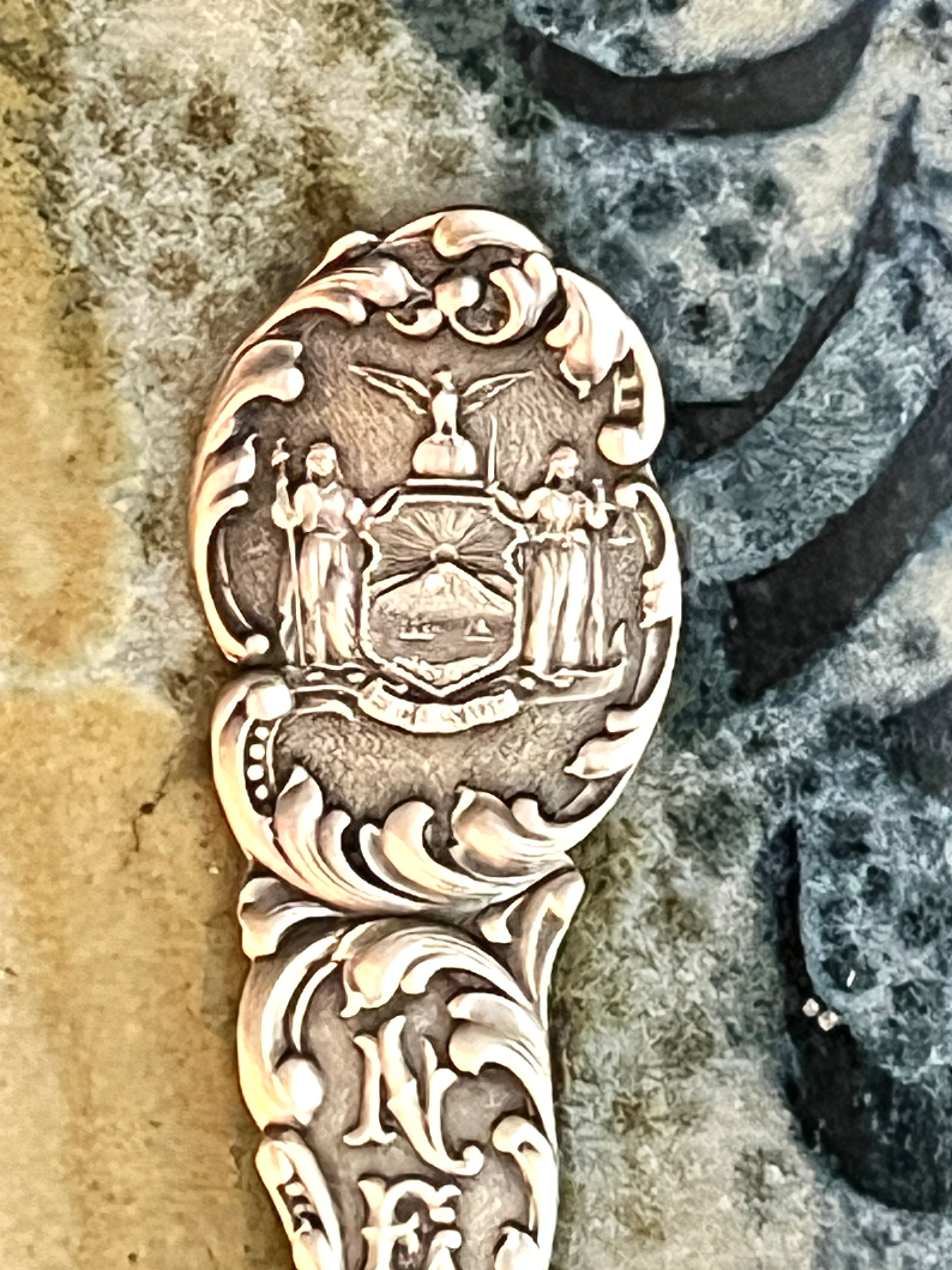 Decorative silver spoon with intricate designs on a stone surface