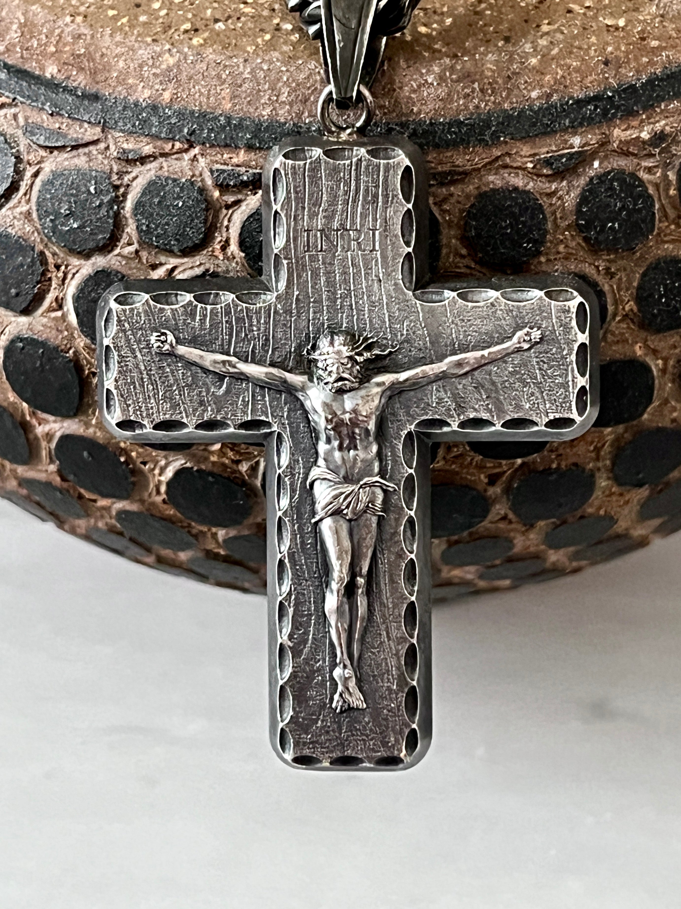 Silver crucifix pendant on a textured background