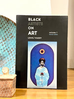 Load image into Gallery viewer, Rare Copy of Black Artists on Art  1976 Edited by Samella Lewis and Ruth Waddy. The cover features an image of a painting of a Black Woman in blue with an afro &amp; large Hoop earrings floating in a blue background with a moon, sun, and flower. There are artifacts surrounding the book, a blue bowl and  a brown patterned box. 
