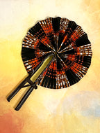 An open Ulla Johnson hand fan with Ankara wax print design, featuring a leather handle and closure, displayed against an abstract background.